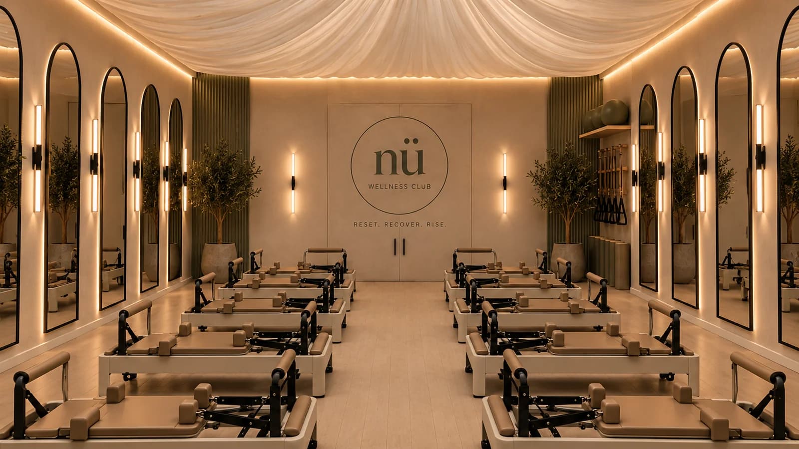The reformer Pilates studio at Nü, with rows of reformers beneath a draped ceiling and the Nü roundel on the far wall